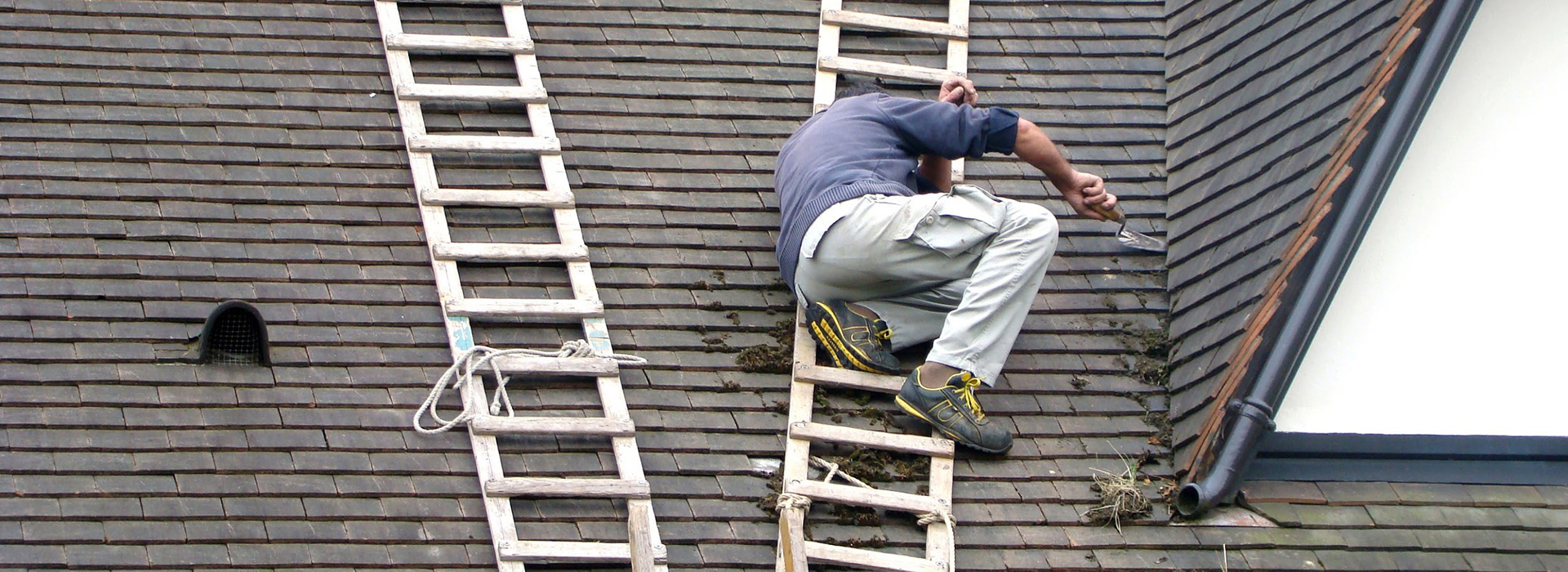 Couvreur entrain de démousser sur le toit d'une maison dans le Val de Marne